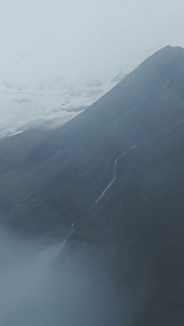 waterfall in misty blue mountain scenery, vertical video for social media instagram reels and tiktok of dramatic atmospheric moody rocky rugged mountains landscape in the himalayas in nepal