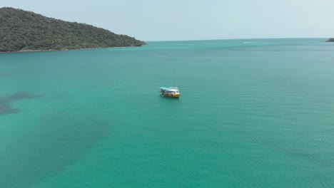 Barco-Camboyano-Solitario-En-Medio-Del-Mar-Turquesa-Paradisíaco-En-La-Bahía-De-M&#39;pai,-Koh-Rong-Sanloem,-Camboya---Sobrevuelo-De-Vista-Aérea-Superior