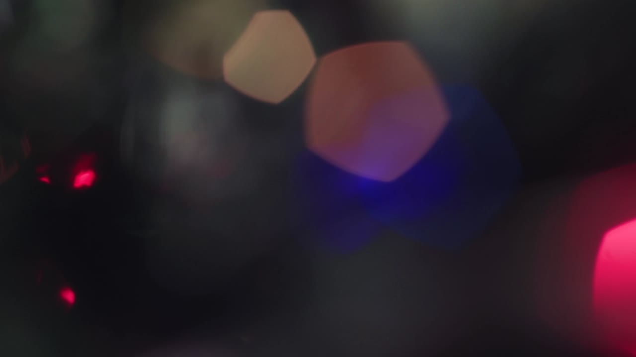Christmas colored lights move and flicker out of focus.