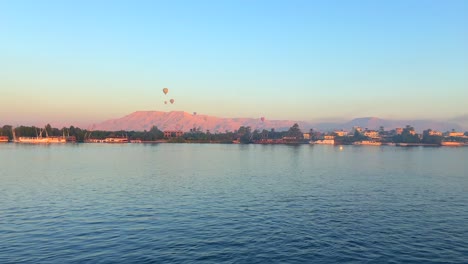 4k static scenic clip of several hot air balloons flying over the valley of the kings and the egyptian nile river at sunrise