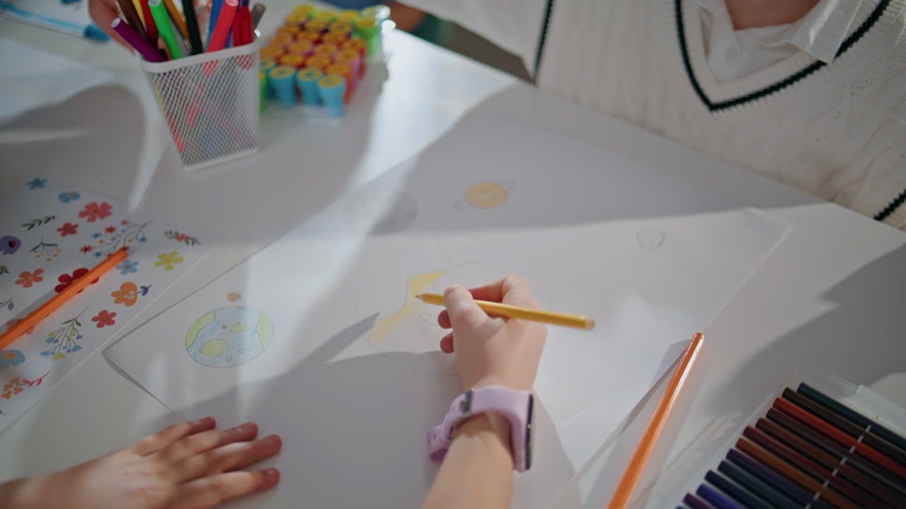 Small girl drawing picture in art workshop closeup. Talented kid holding pencil