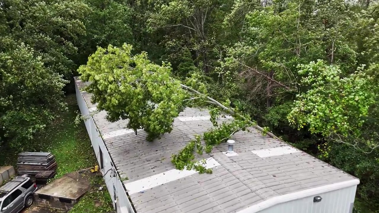 Aerial drone footage in Greenville, South Carolina of flooding from Hurricane Helene with trees fallen on garage