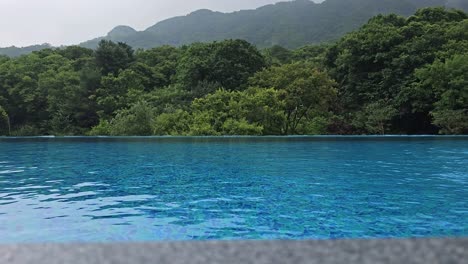 emptry infinity swimming pool with green mountain landscape - low angle