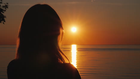 Silhouette-Einer-Frau-Mittleren-Alters,-Die-Den-Sonnenuntergang-über-Dem-Meer-Beobachtet