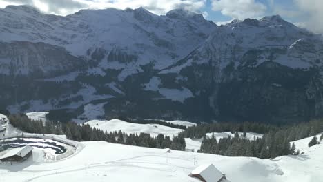 un dron aéreo se mueve hacia adelante disparado sobre la cordillera cubierta de nieve en engelberg brunni bahnen a lo largo de los alpes suizos en suiza en una mañana de invierno