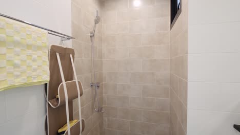 baño de azulejos beige simple y limpio con cabezal de ducha