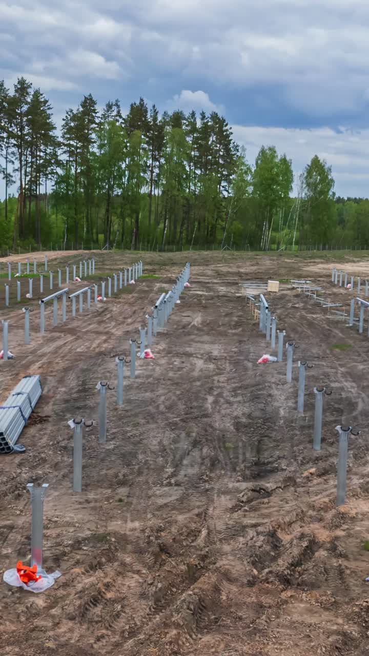 Steel posts installed in cleared field during solar panel construction, vertical