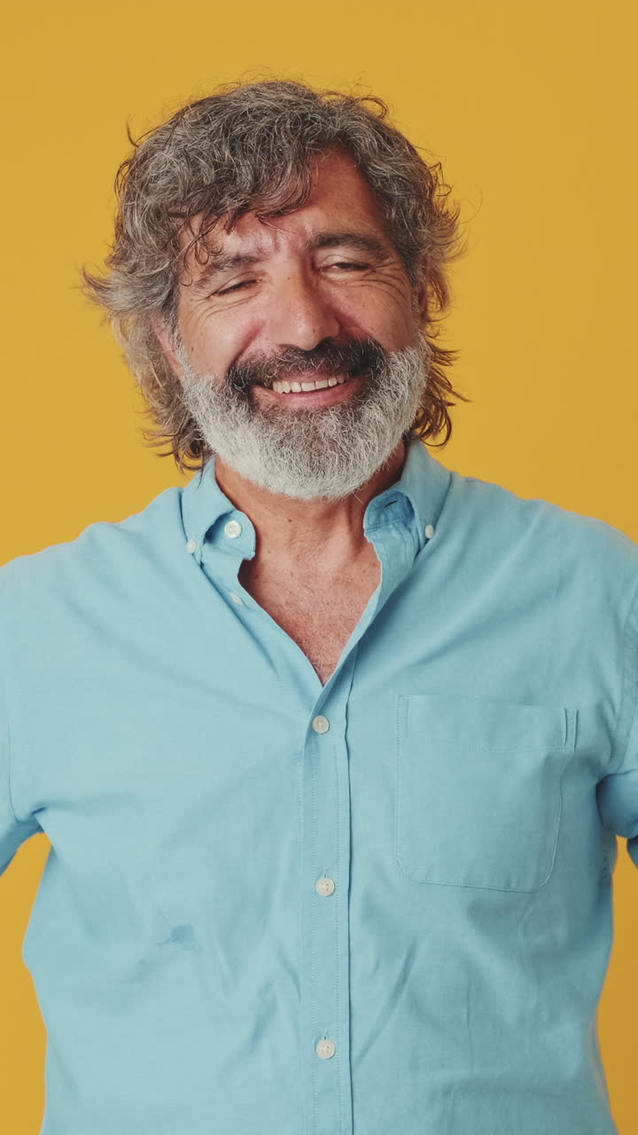 Uomo barbuto felice in camicia blu sorridente alla fotocamera
