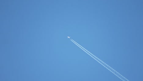 jet airliner flying high in the sky leaves contrails in the clear blue sky.