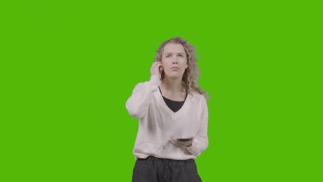 studio shot of young woman listening to music on mobile phone and dancing against green screen 5