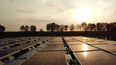 aerial backwards flight showing solar panels reflection from sun during golden sunset