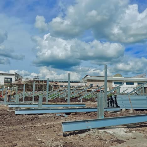 building of a new solar farm. teamwork of engineers constructing metal basis for solar panels under cloudy sky. time lapse.