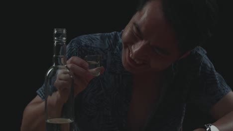 close up of drunk asian man cheering vodka with bottle glass before drinking in black background