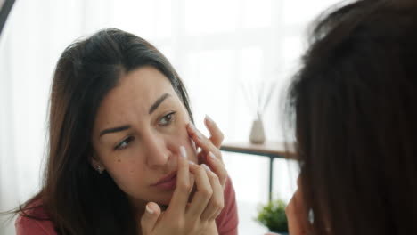 woman checking her skin in the mirror