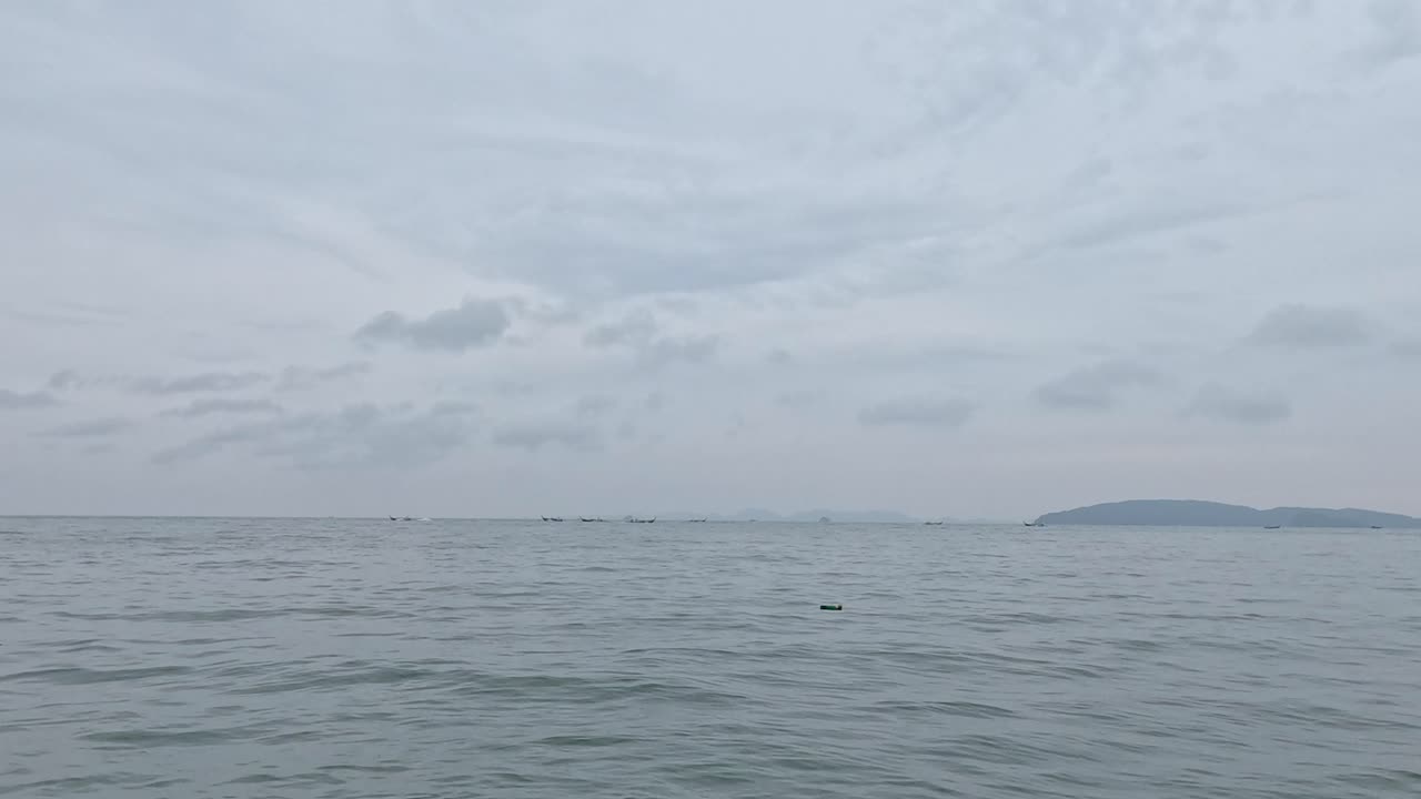 평화로운 바다 풍경과 구름이 가득한 하늘 아래의 먼 섬