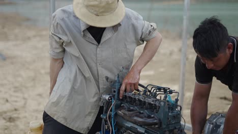 two workers repairing a diesel engine