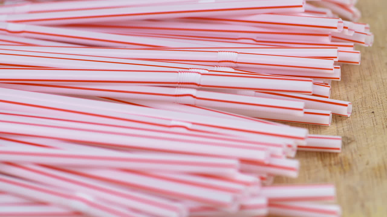 un montón de popotes de plástico arrojados sobre una superficie de madera