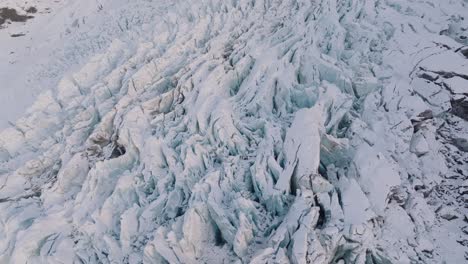 aerial view over textured ice formations in falljokull glacier covered in snow, iceland, at sunset