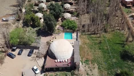 Drone-flying-over-Geodesic-domes-in-Chilean-desert-with-a-pool