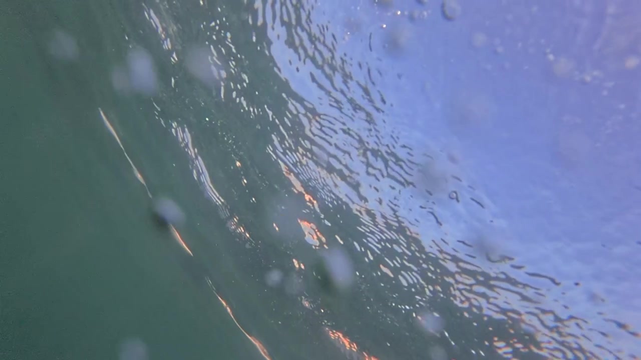 Water bubbles moving underwater in green liquid, abstract background with sunlight reflecting on the surface