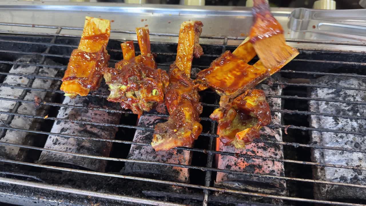 Costine in salsa grigliate e spennellate su un barbecue caldo.