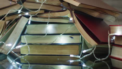 video of christmas fairy lights and stack of books on wooden background