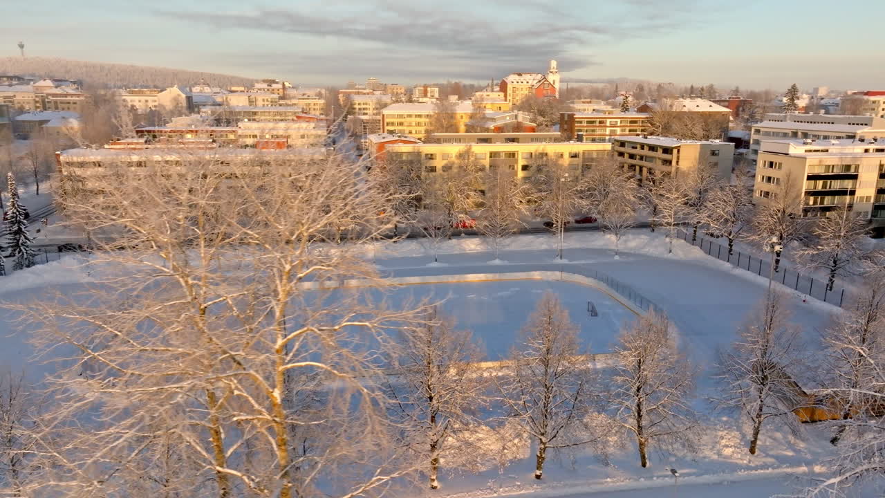 AERIAL: Freezing morning at a quiet ice hockey rink, winter sunrise in Finland