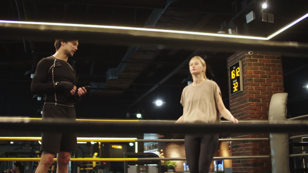 спортивная девушка, использующая скакалку в тренажерном зале. тренер дает советы, чтобы девушка входила в клуб