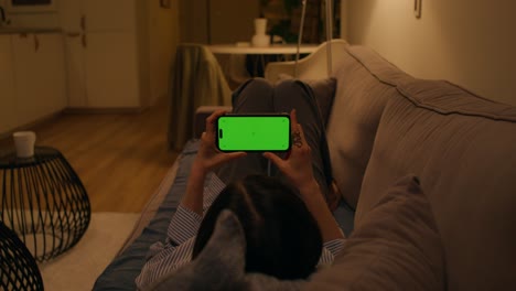 woman watching phone on couch at night