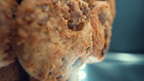 A-vertical-macro-close-up-shot-of-a-pile-full-of-crispy-chocolate-chip-cookies,-on-a-360-rotating-stand,-studio-lighting,-super-slow-motion,-120-fps,-Full-HD-video