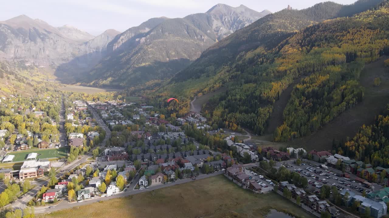 una toma giratoria de un avión no tripulado, de un parapente volando sobre un vecindario en la ciudad de telluride, colorado, en un día soleado en la temporada de otoño