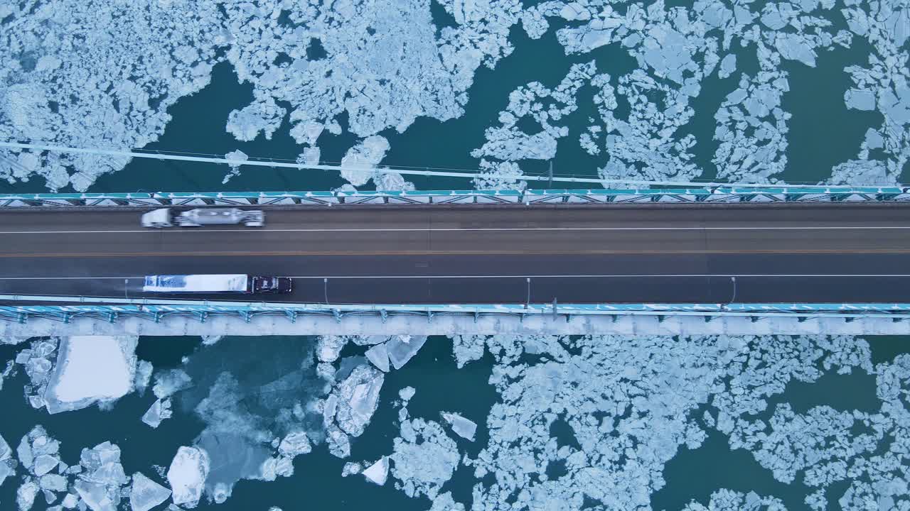 Top view of vehicles crossing icy river over the bridge