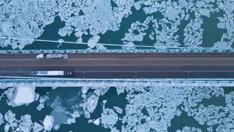 top view of vehicles crossing icy river over the bridge