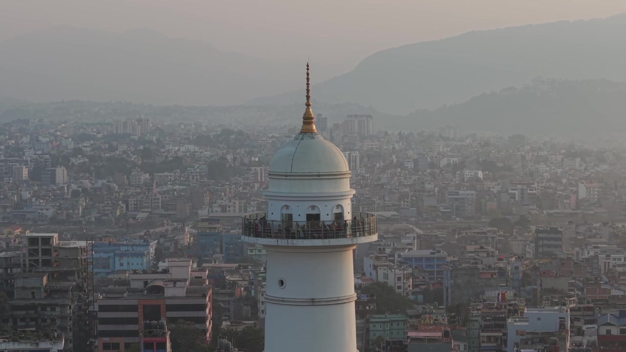 Turistit seisovat Dharahara-tornin näköalaparvekkeella Kathmandussa, Nepalissa. Kaunis historiallinen valkoinen monumentti avautuu sumuisen aamun kaupunkikuvaan drone-lennon aikana kuvattuna