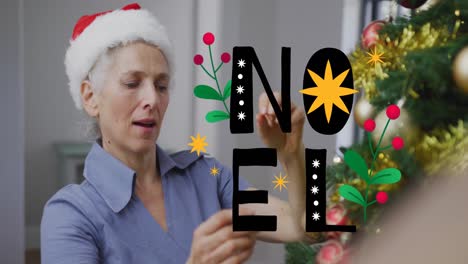 animation of noel text over senior caucasian woman wearing santa hat