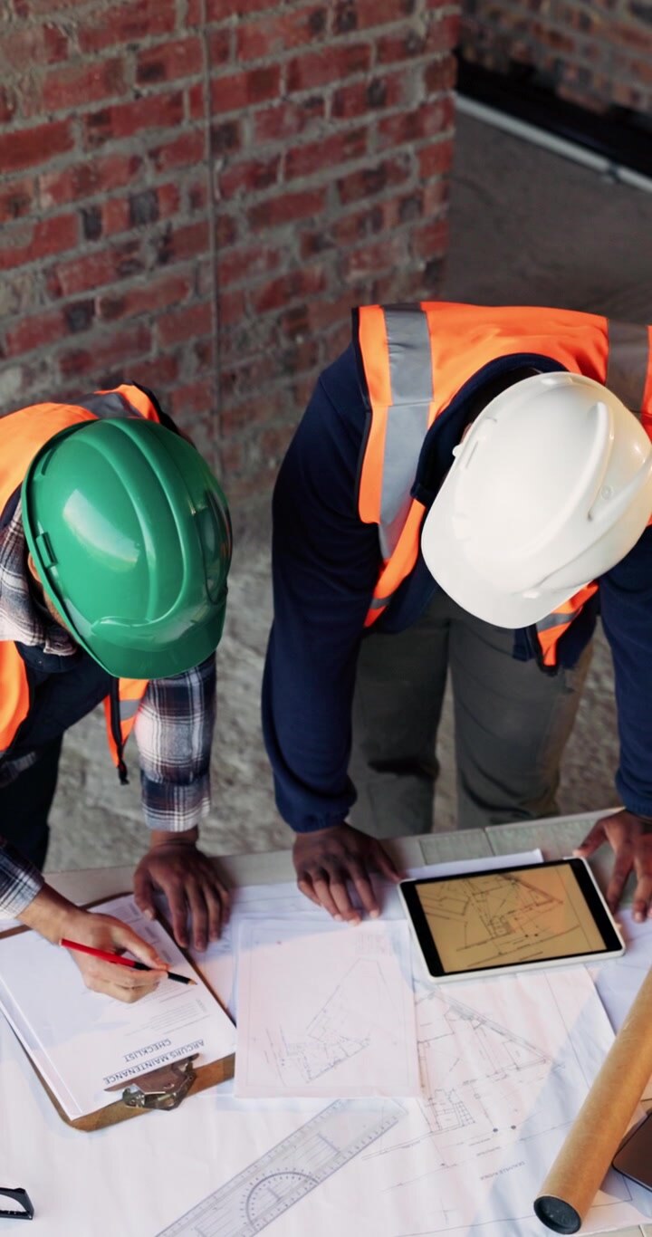 Construction Engineers Reviewing Blueprints and Tablet on Site