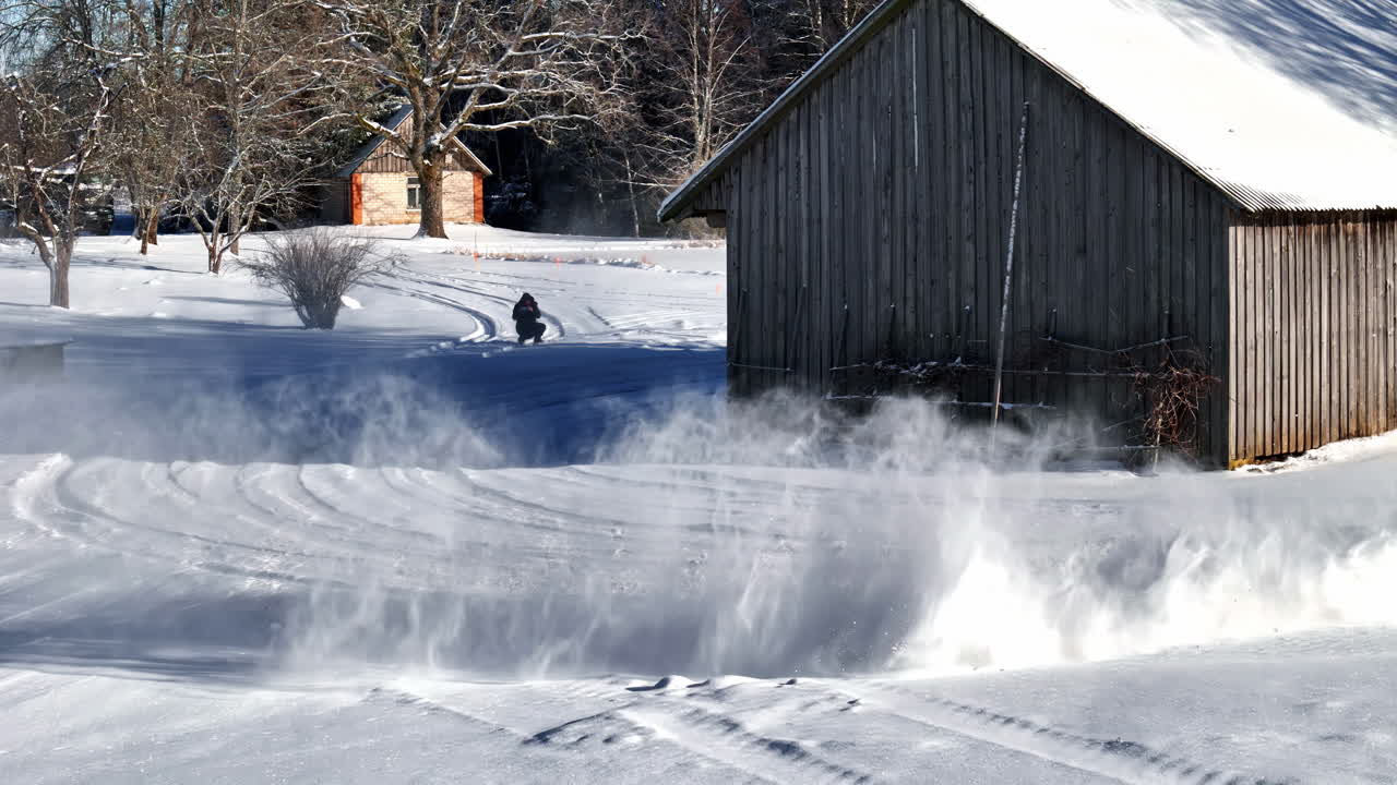 Snowy backyard with wooden house as car drifts in slow motion around edge, quiet winter setting