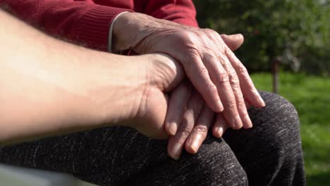 gentle connection: man supports mature woman's hands with rheumatoid arthritis outdoors