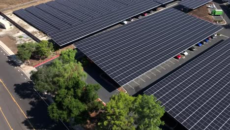 Aerial-view-of-a-large-solar-panel-covered-parking-lot-of-a-commercial-building-along-the-side-of-a-road