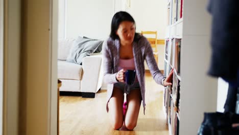 Mujer-Seleccionando-Un-Libro-De-Una-Estantería-En-El-Salón