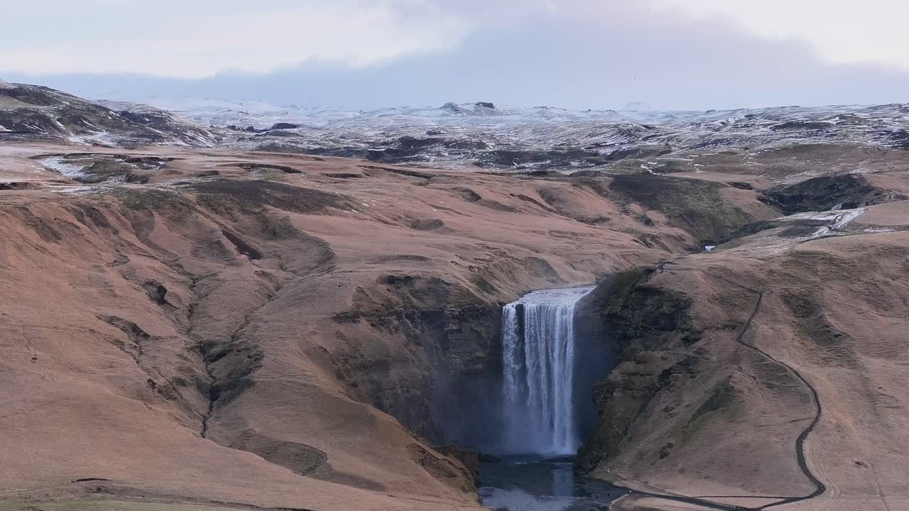 aerial - Skógafoss waterfall in snowy Icelandic valley near Eyjafjallajökull