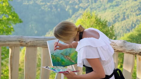 woman painting mountain landscape outdoors