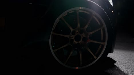 Detail-shot-of-the-front-golden-wheel-with-low-profile-tires-of-a-sports-car-at-night