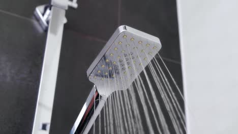 cascada de agua refrescante desde el elegante cabezal de ducha de cromo en el baño