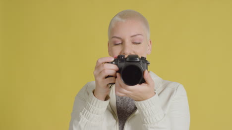 кавказская модель позирует с фотоаппаратом на желтом фоне 04