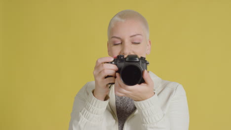 modelo caucásica femenina posando con dslr contra fondo amarillo 04