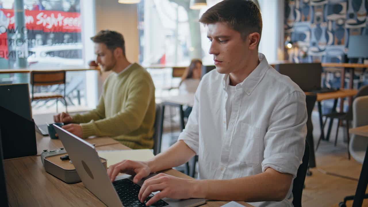 Serious guy staring computer monitor at buro closeup. Man typing laptop office