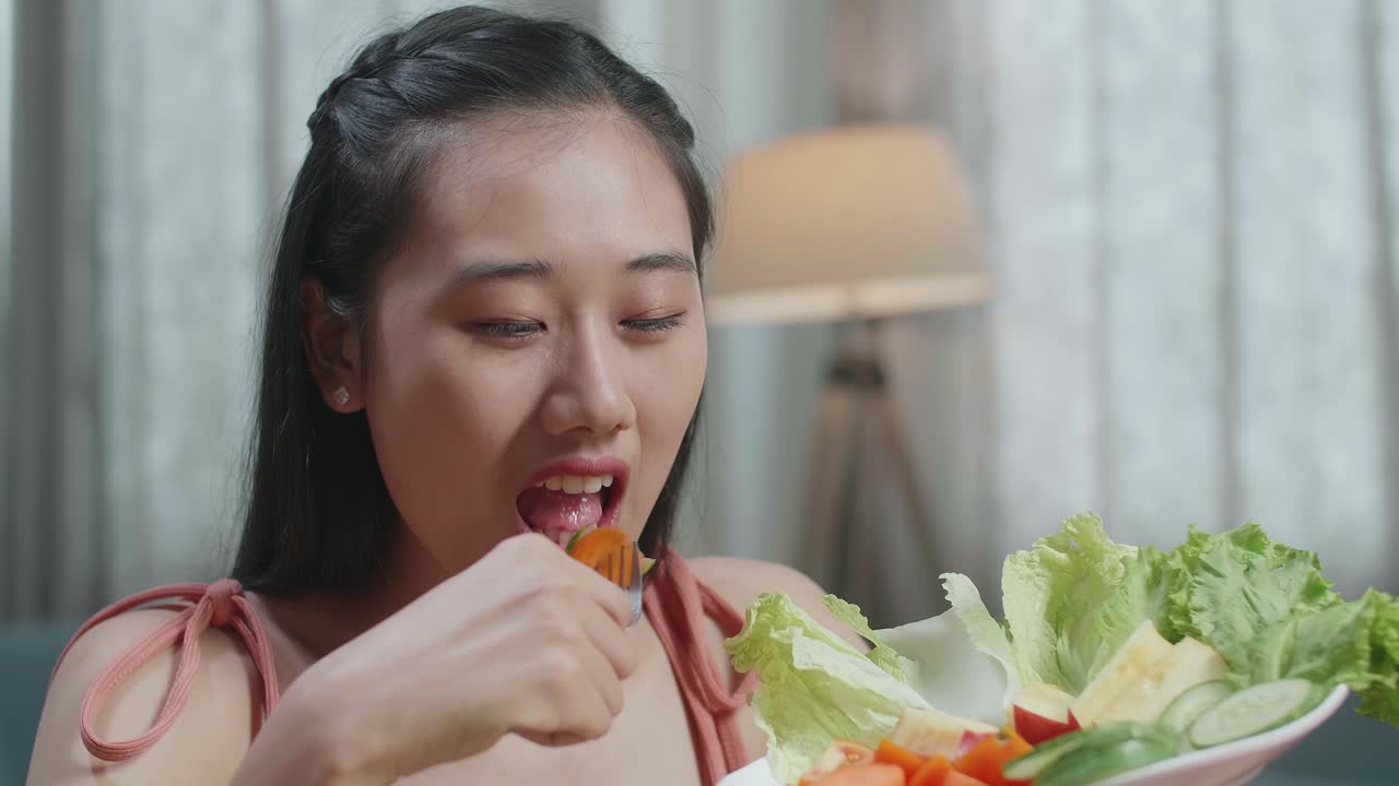 미소 짓고 엄지손가락을 올리기 전에 건강한 음식을 먹는 아시아 여성의 클로즈업 집에서 카메라에 제스처