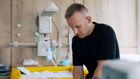 worried caucasian male in the hospital room with his wife delivering a baby. concerned man looks down.
