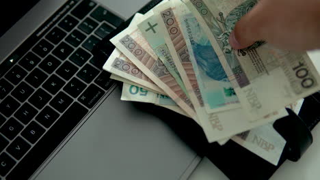 el hombre puso billetes polacos con billetera negra en la computadora portátil, dinero polaco y moneda nacional